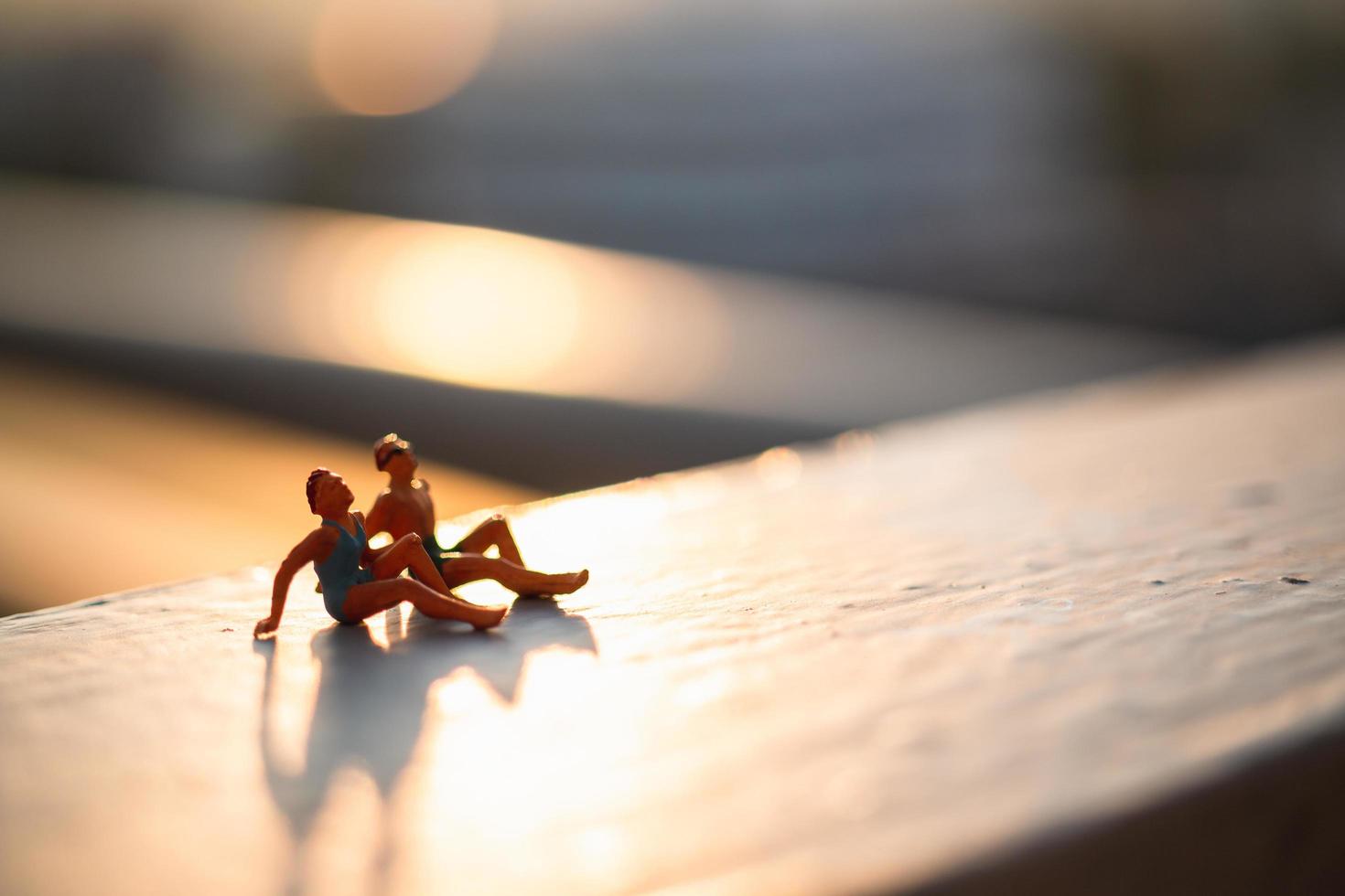 Miniature people wearing swimsuits relaxing with natural sunlight, summertime concept photo