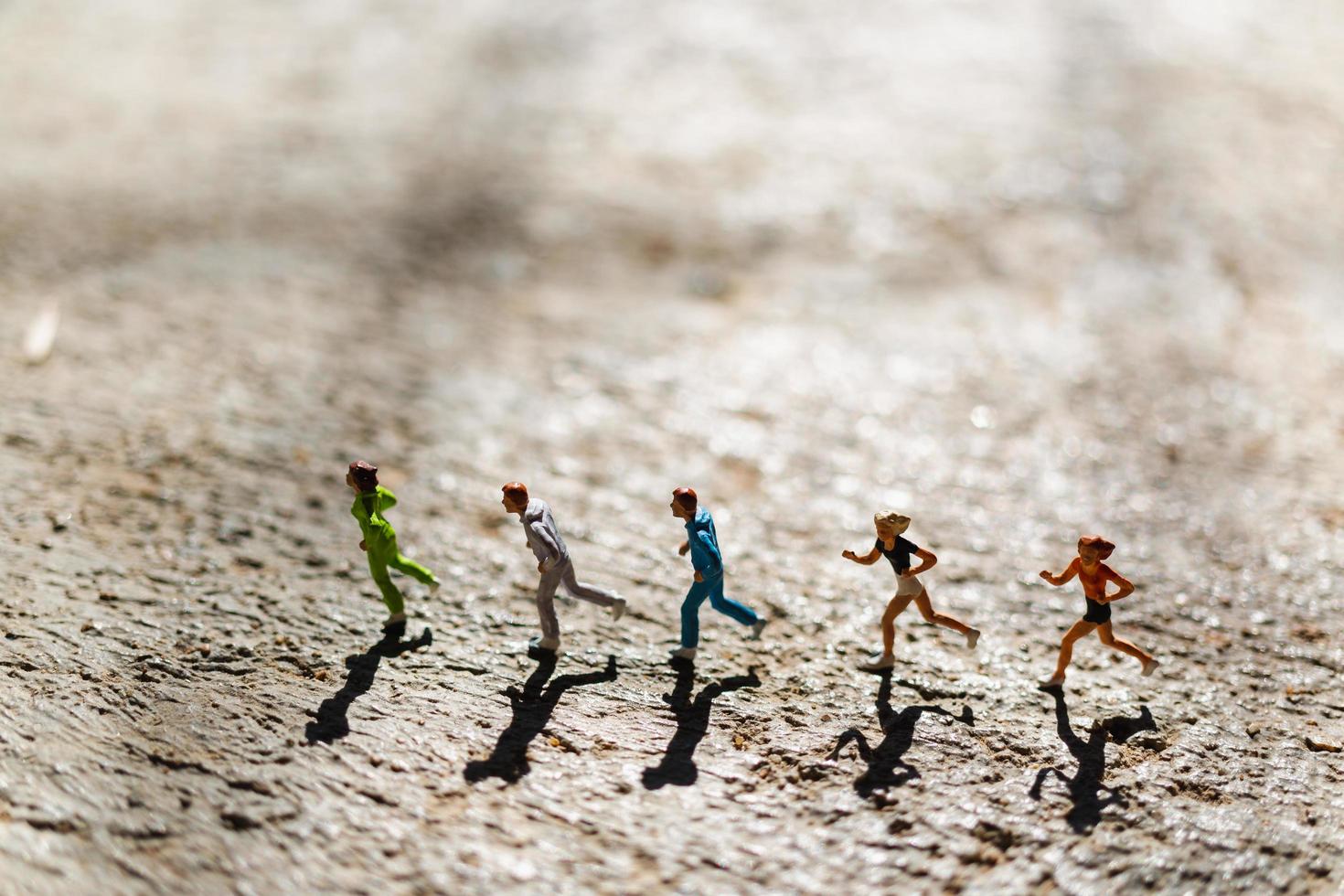 Grupo en miniatura de personas corriendo sobre un piso de concreto, concepto de estilo de vida saludable foto