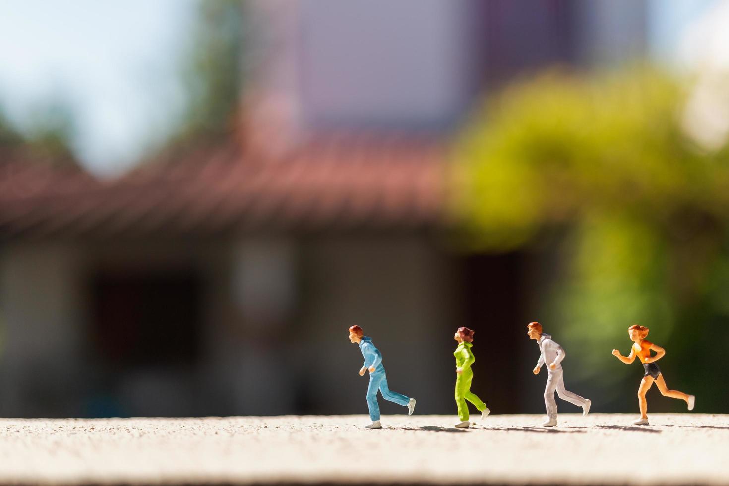 Grupo en miniatura de personas corriendo en una carretera de hormigón, concepto de estilo de vida saludable foto