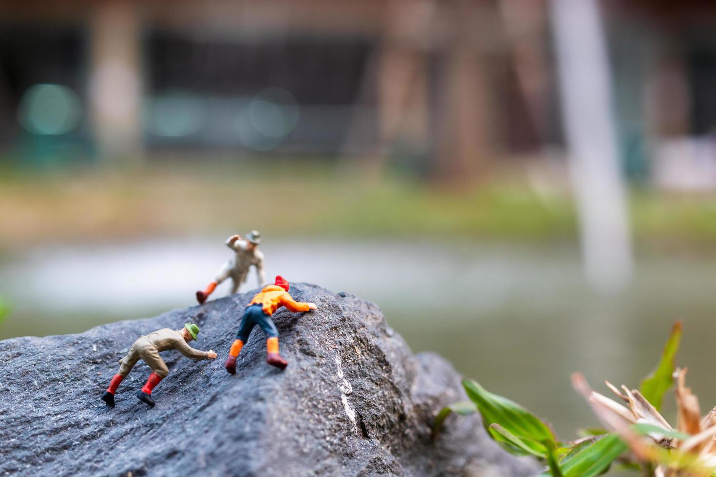 Miniature hikers climbing up on a rock, sports and leisure concept photo