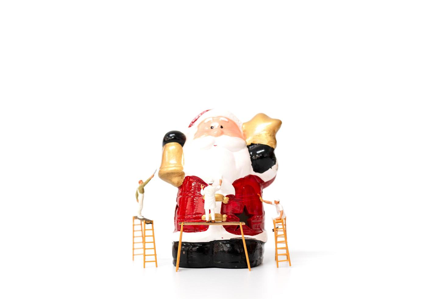Miniature team of workers painting a Christmas prop on a white background, Merry Christmas and Happy new year concept photo