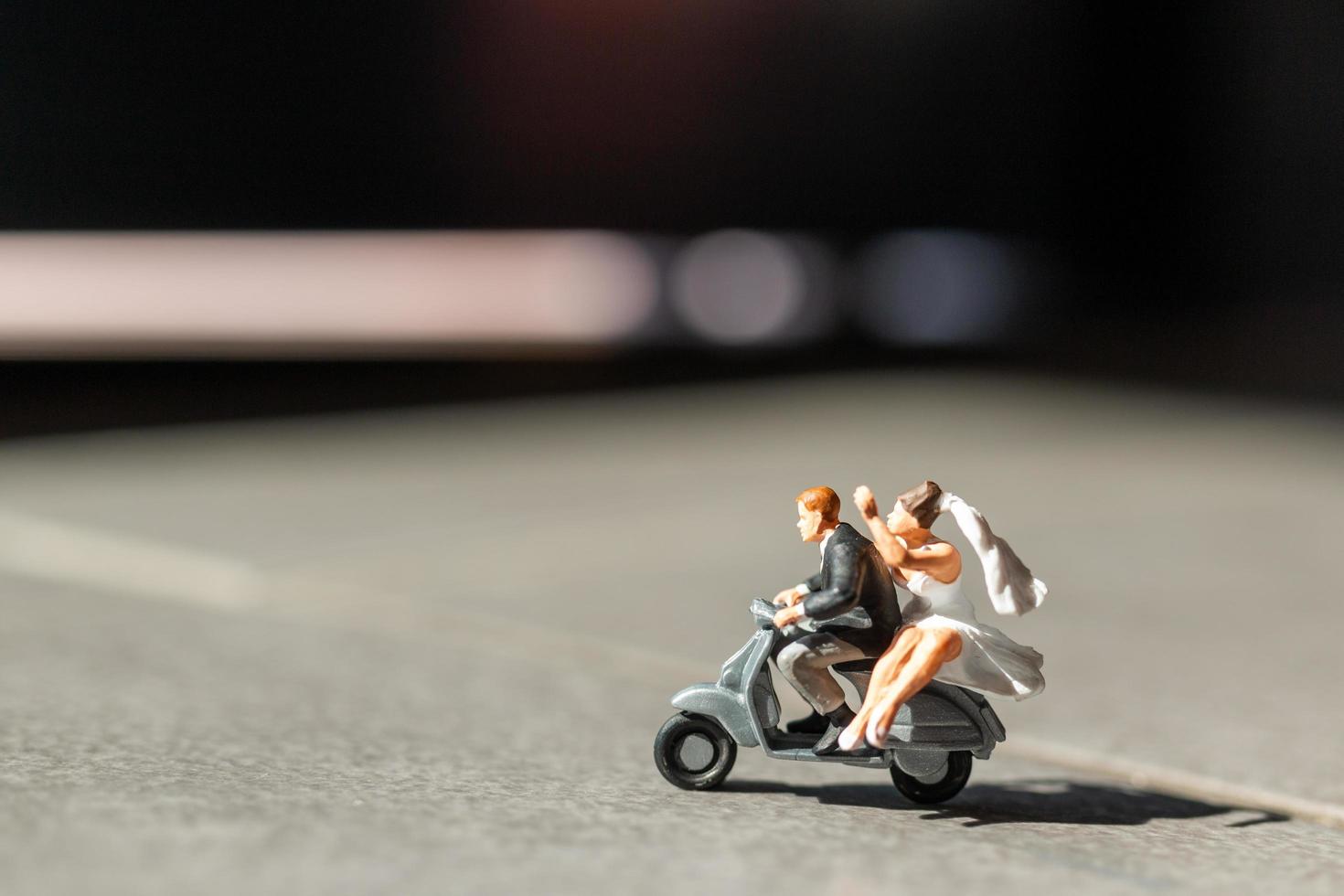 Pareja en miniatura enamorada en moto, concepto de aventura y vacaciones foto