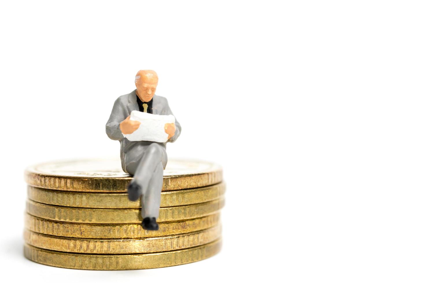 Miniature businessman sitting on a stack of coins, money and financial concept photo