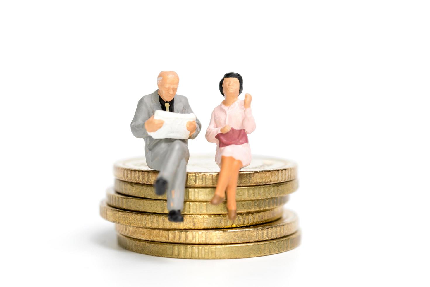 Miniature businesspeople sitting on a stack of coins, money and financial concept photo