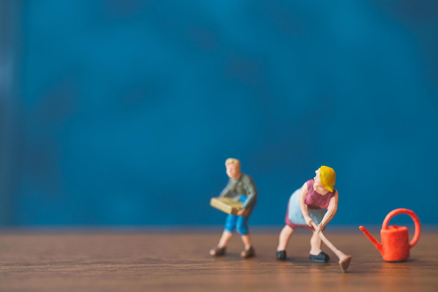 Miniature gardeners standing in front of a blue wall background photo