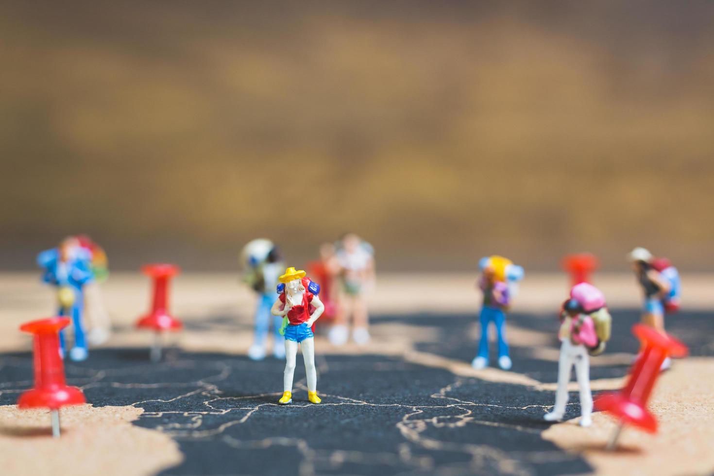 Miniature backpackers walking on a world map, tourism and travel concept photo