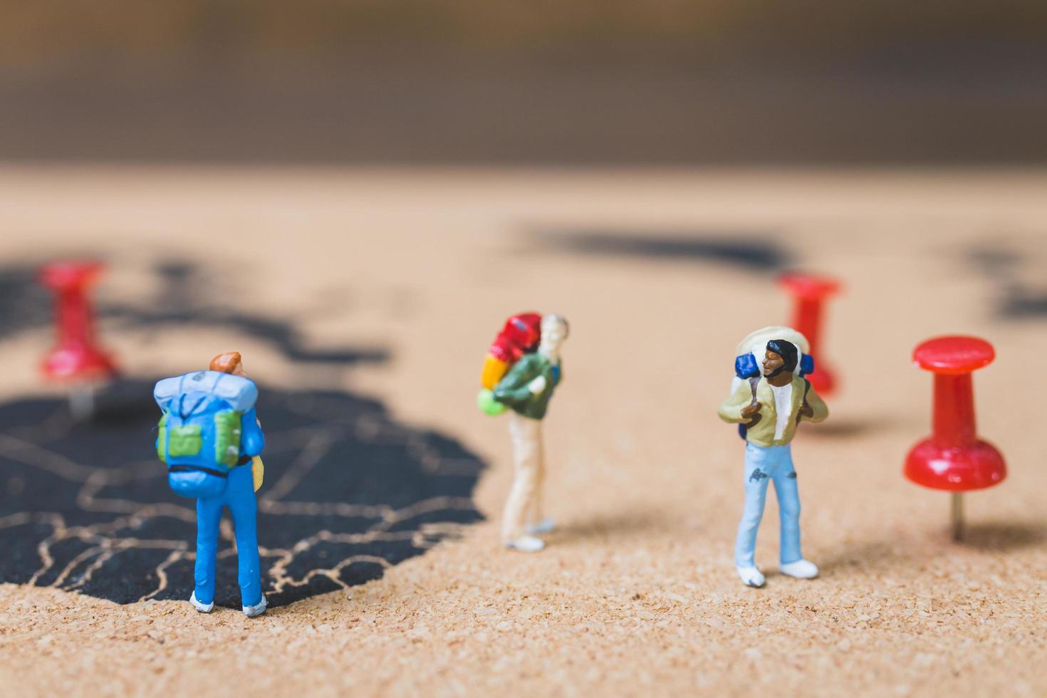 Miniature backpackers walking on a world map, tourism and travel concept photo