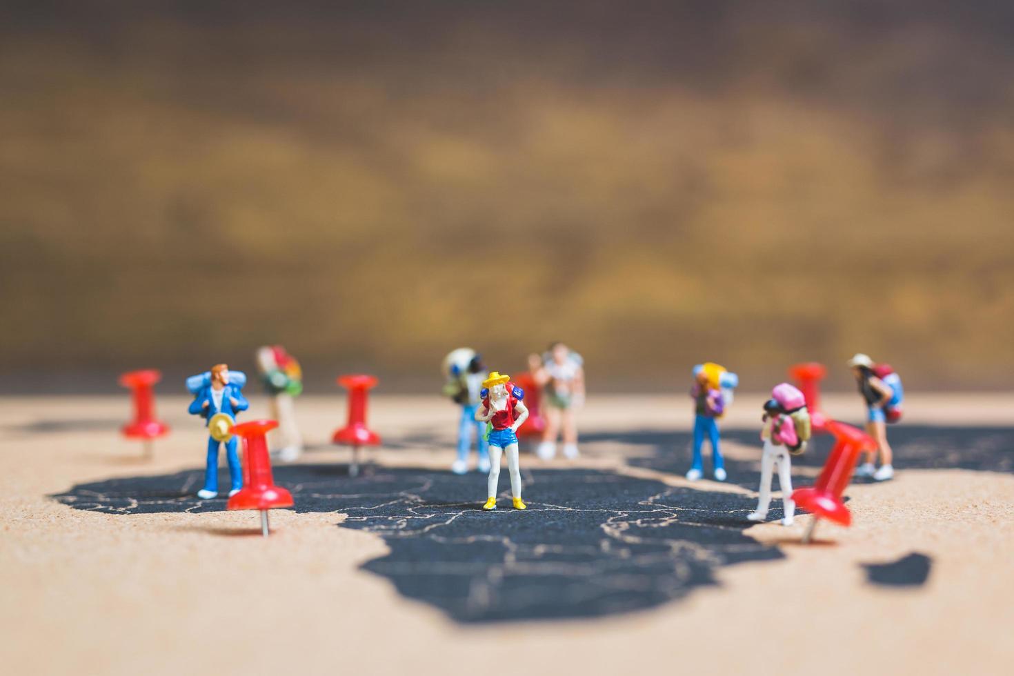 Miniature backpackers walking on a world map, tourism and travel concept photo