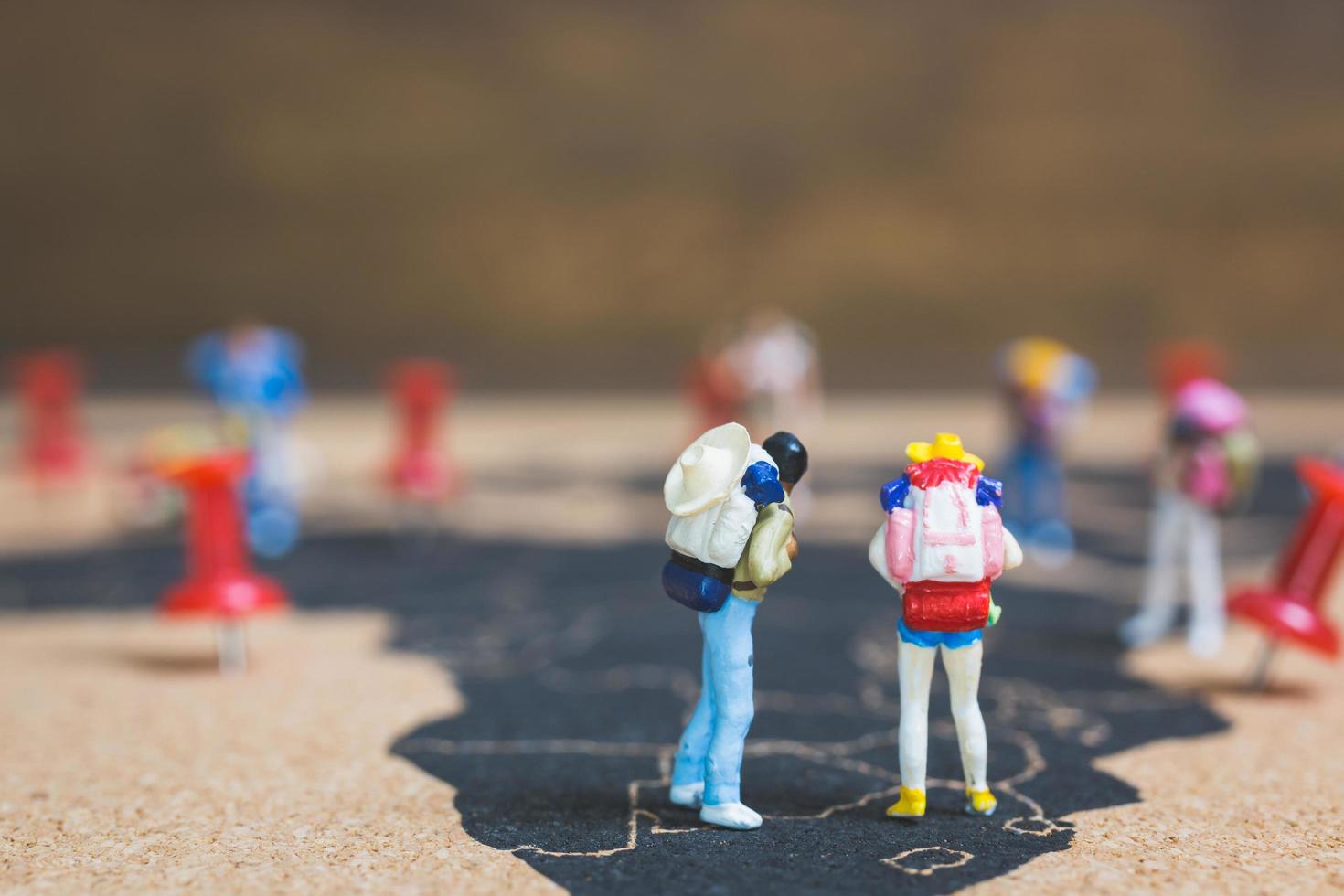 Mochileros en miniatura caminando sobre un mapa del mundo, concepto de turismo y viajes foto