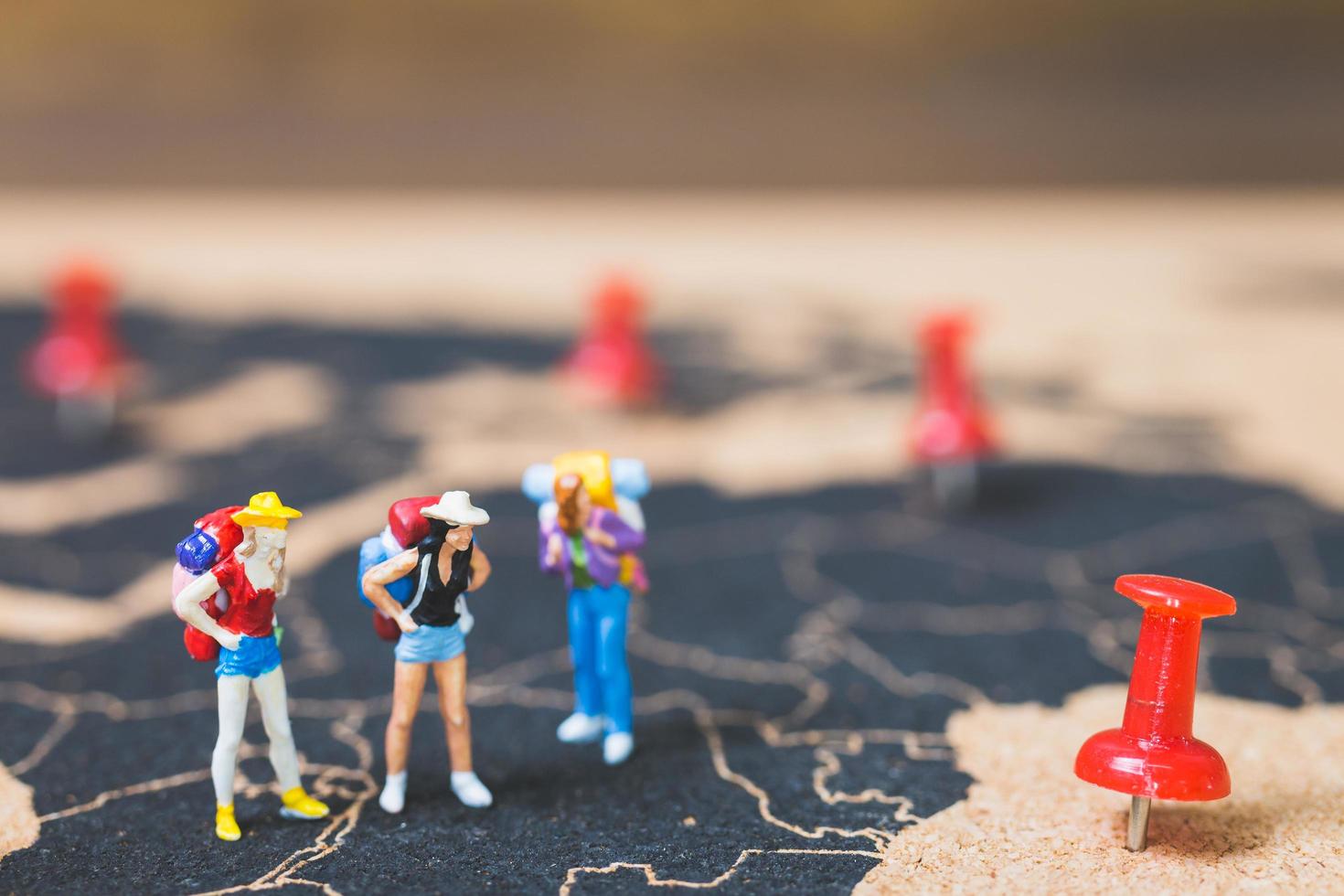 Mochileros en miniatura caminando sobre un mapa del mundo, concepto de turismo y viajes foto