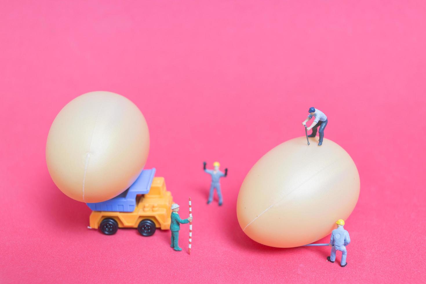 Gente en miniatura trabajando en huevos de pascua para pascua foto