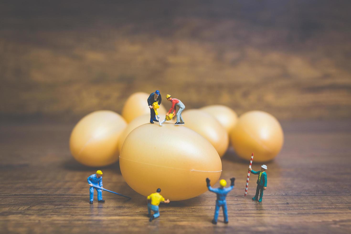 Miniature people working on Easter-eggs for Easter photo