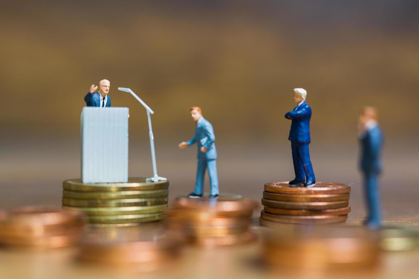 Miniature businessman speaking on a podium on a stack of coins, business and financial investment concept photo
