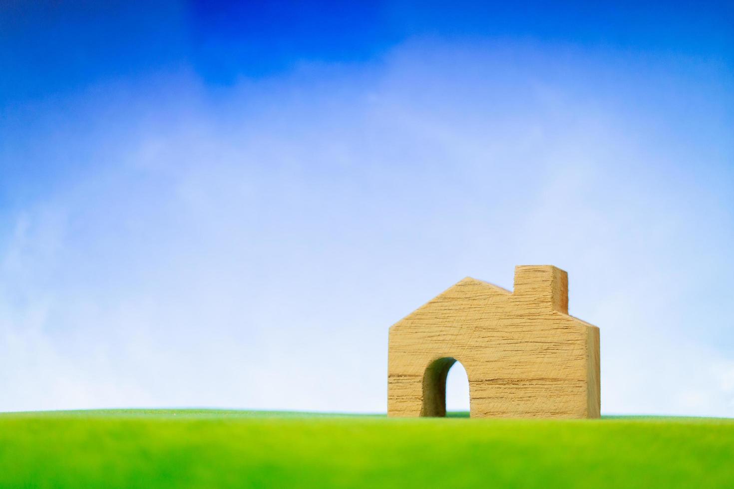 Wooden house model on green grass, eco-friendly house concept photo