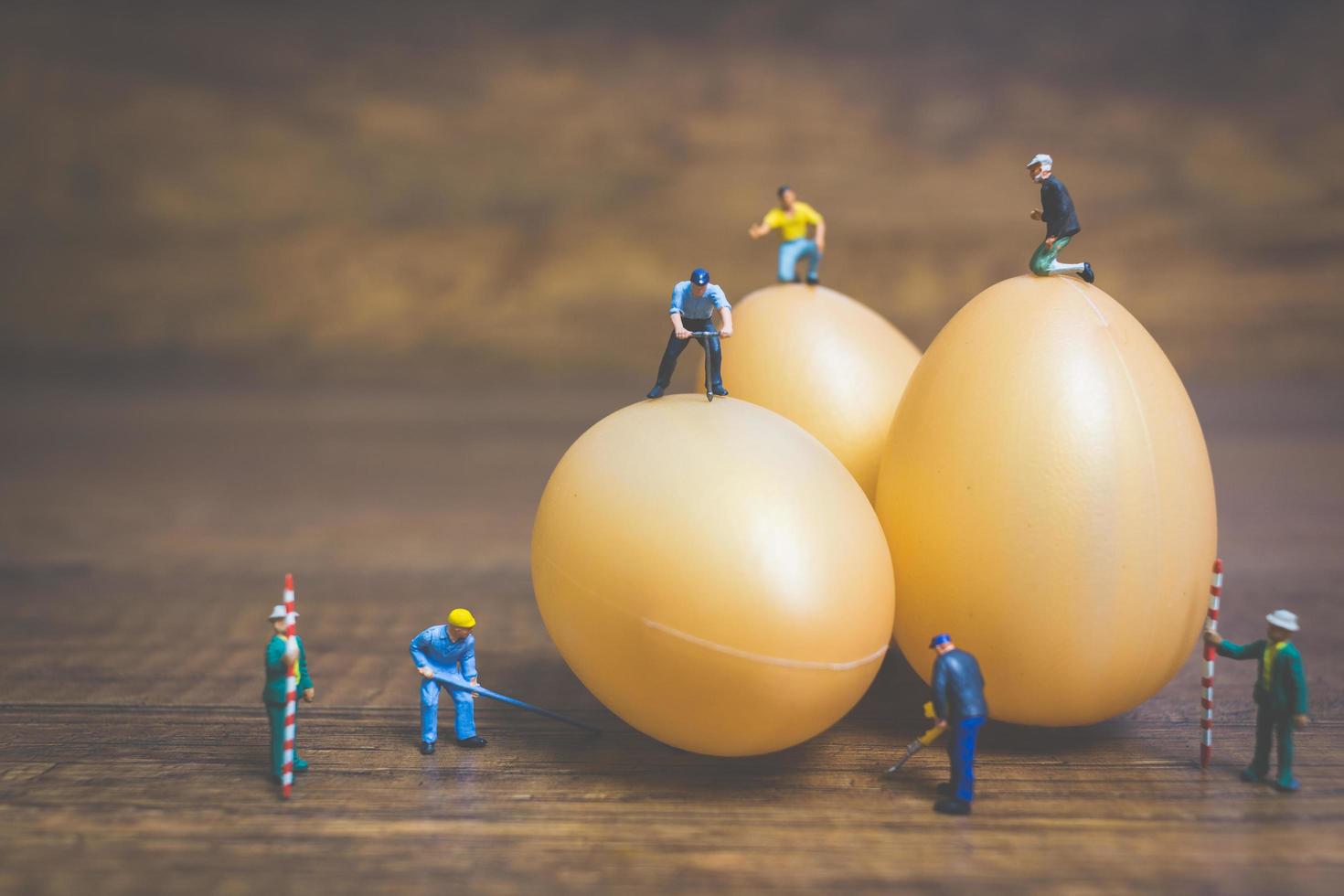 Gente en miniatura trabajando en huevos de pascua para pascua foto