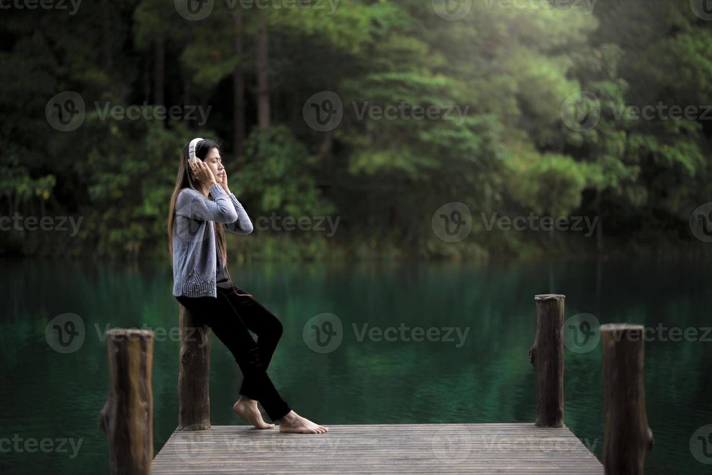 Mujer relajante cerca de un muelle escuchando música foto