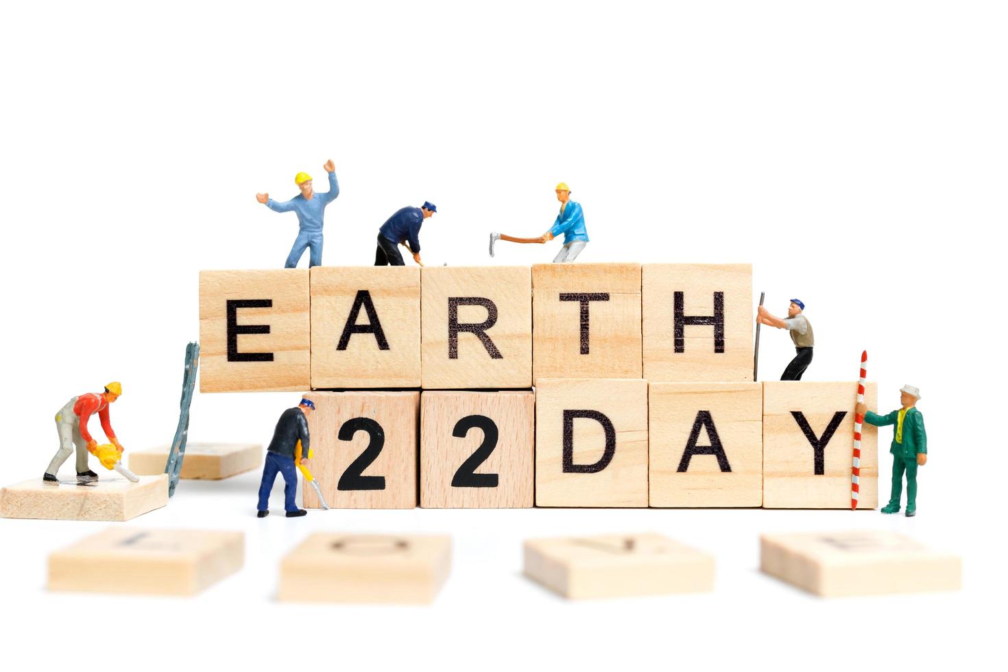 Miniature workers teaming up to build the word Earth Day 22 on wooden blocks, Earth day concept photo