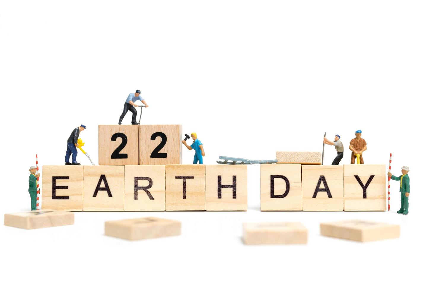 Miniature workers teaming up to build the word Earth Day 22 on wooden blocks, Earth day concept photo