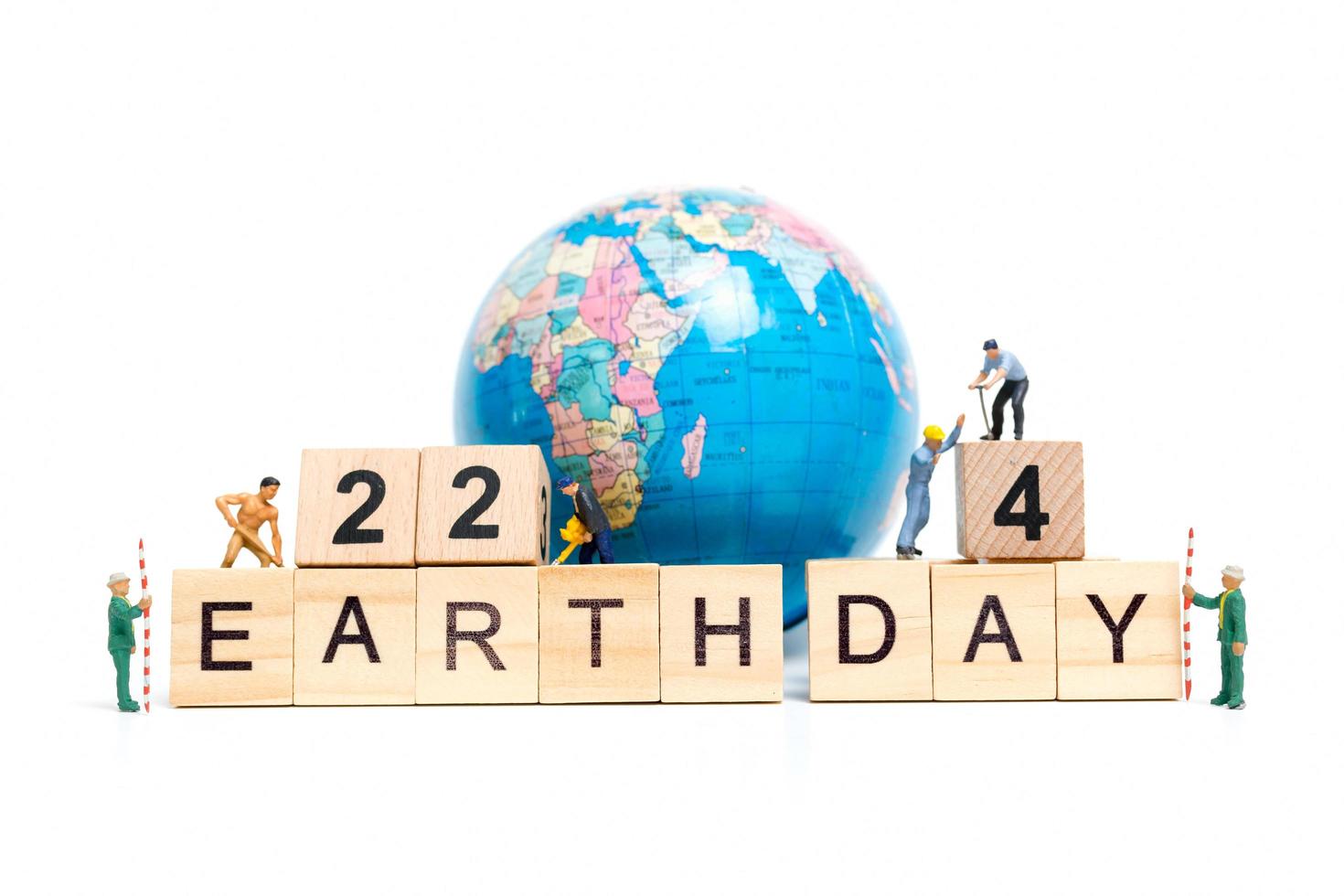 Miniature workers teaming up to build the word Earth Day 22 on wooden blocks, Earth day concept photo