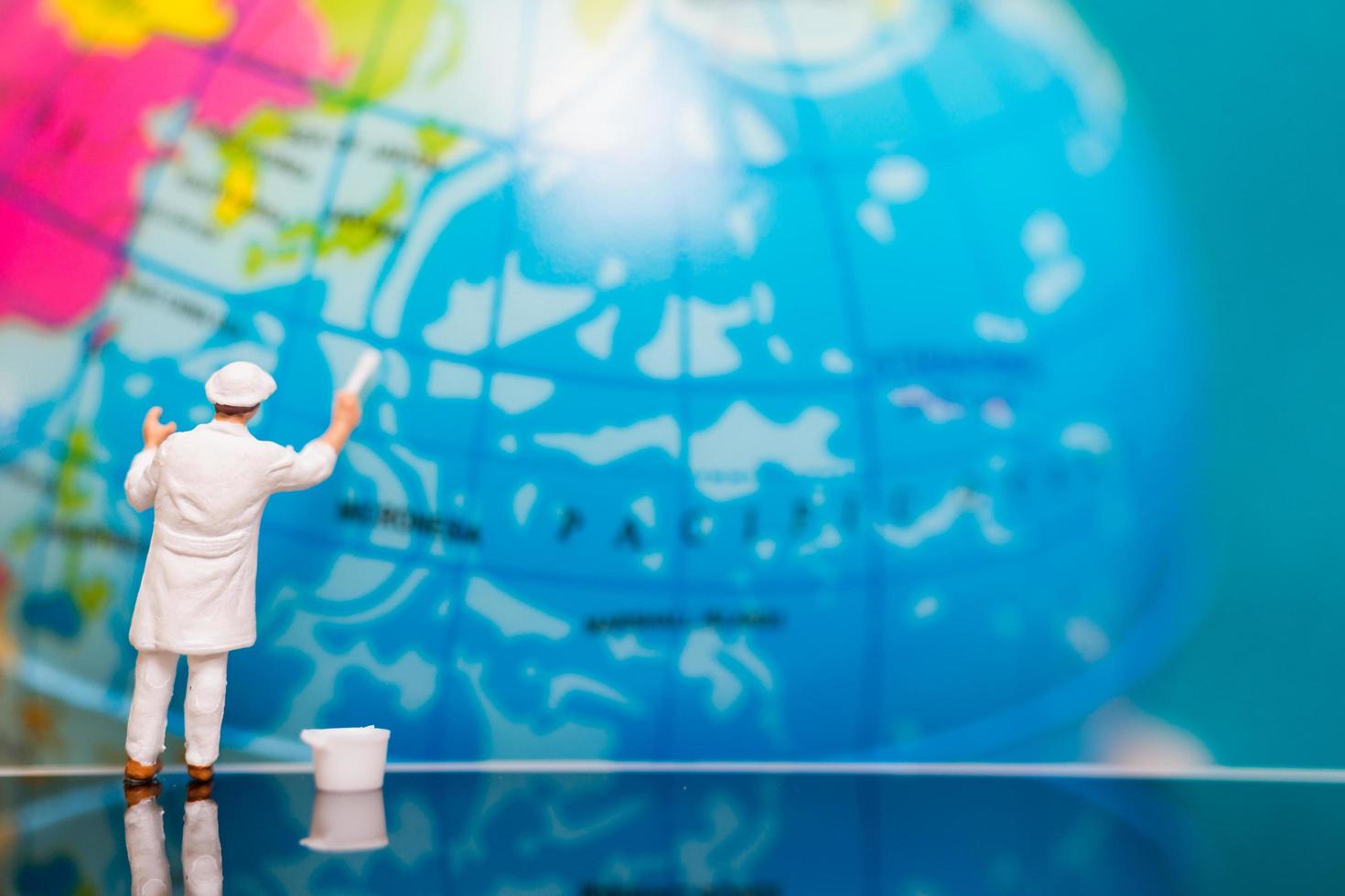 Miniature painter painting on a globe, Earth Day concept photo