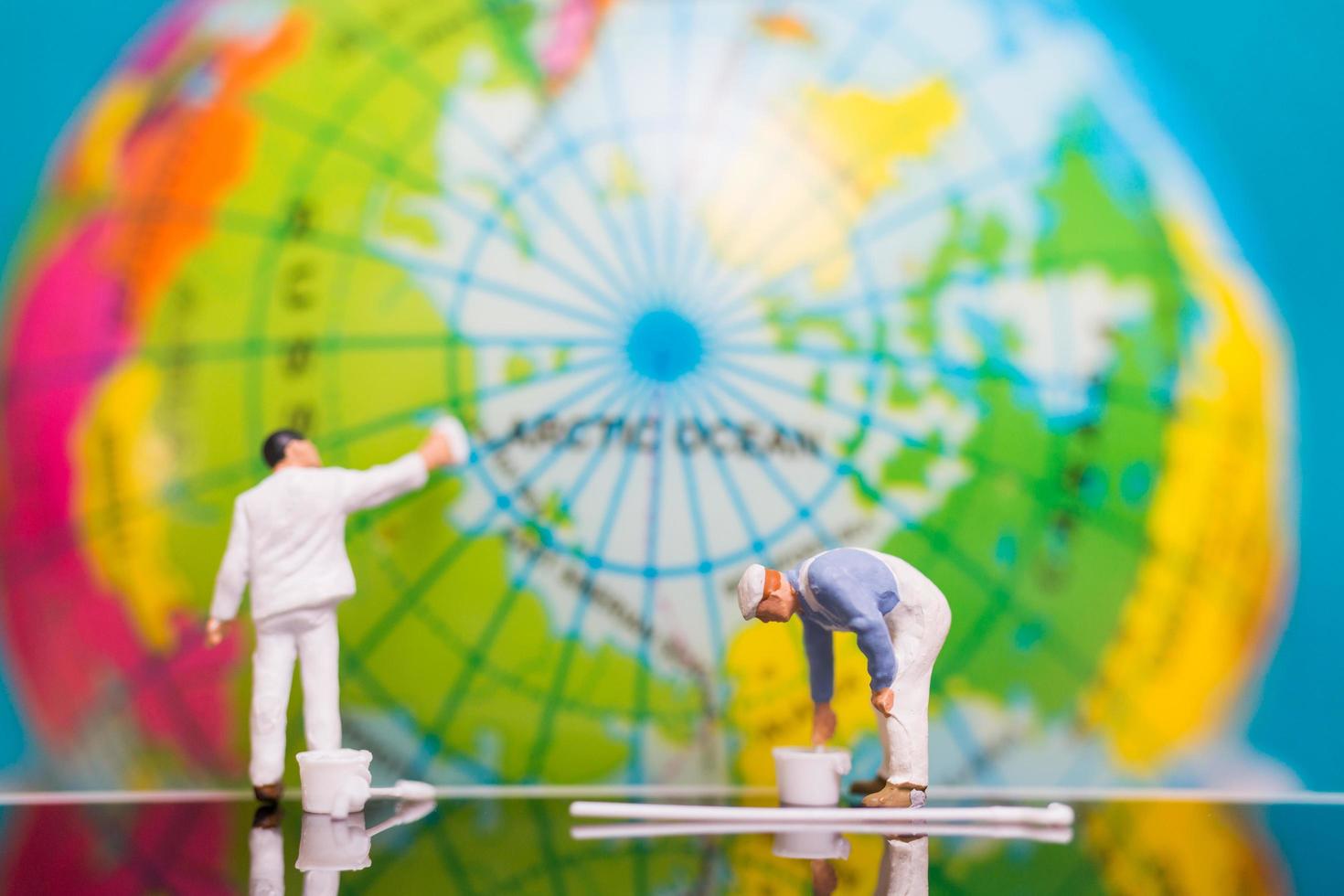 Pintores en miniatura pintando en un globo terráqueo, concepto del día de la tierra foto