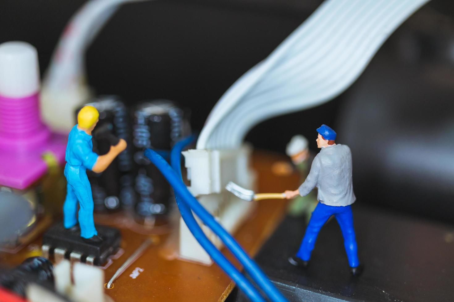 Miniature workers teaming up to repair electronic circuits, construction workers concept photo