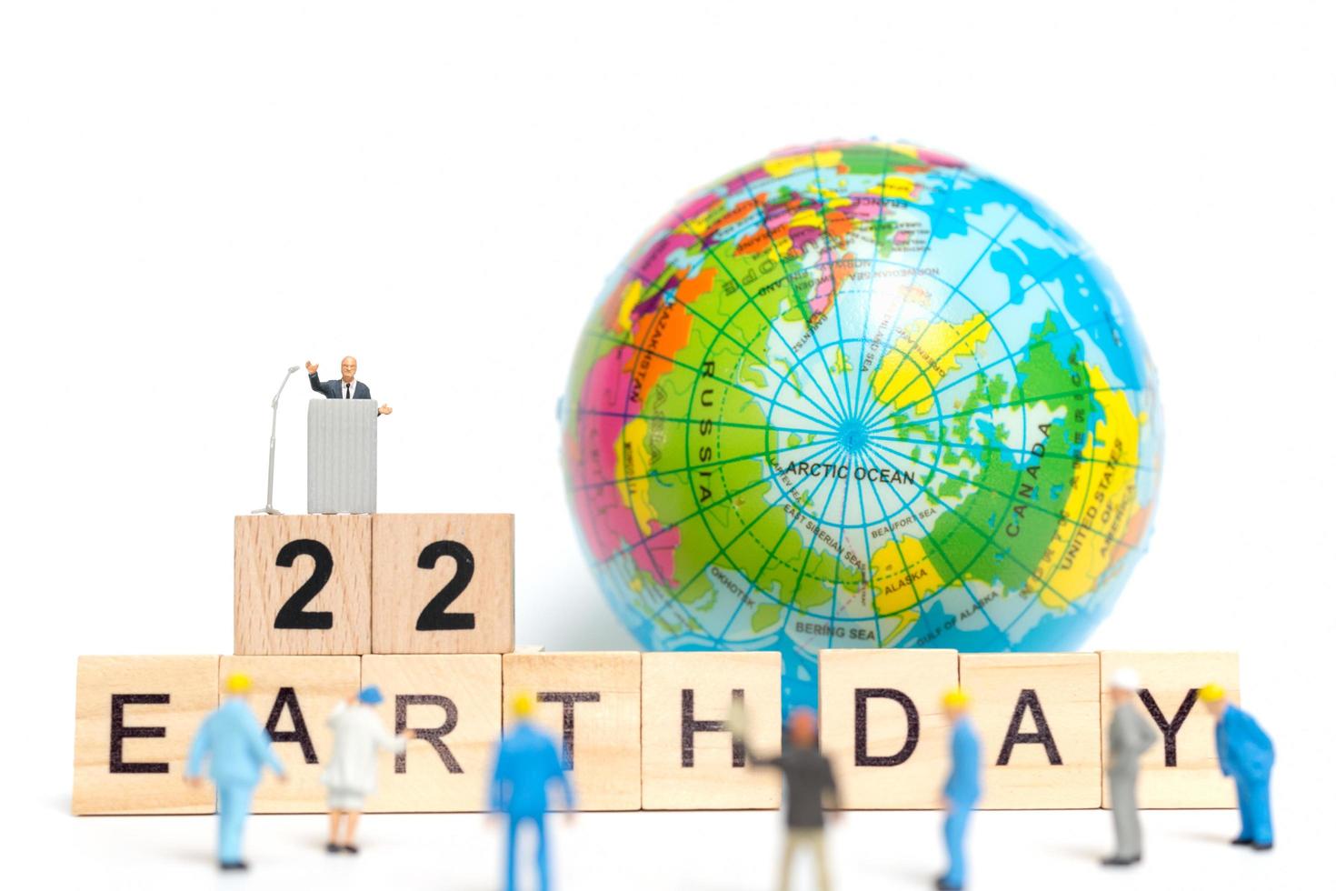 Miniature painters painting on a globe with wooden blocks showing Earth Day 22 on a white background, Earth Day concept photo