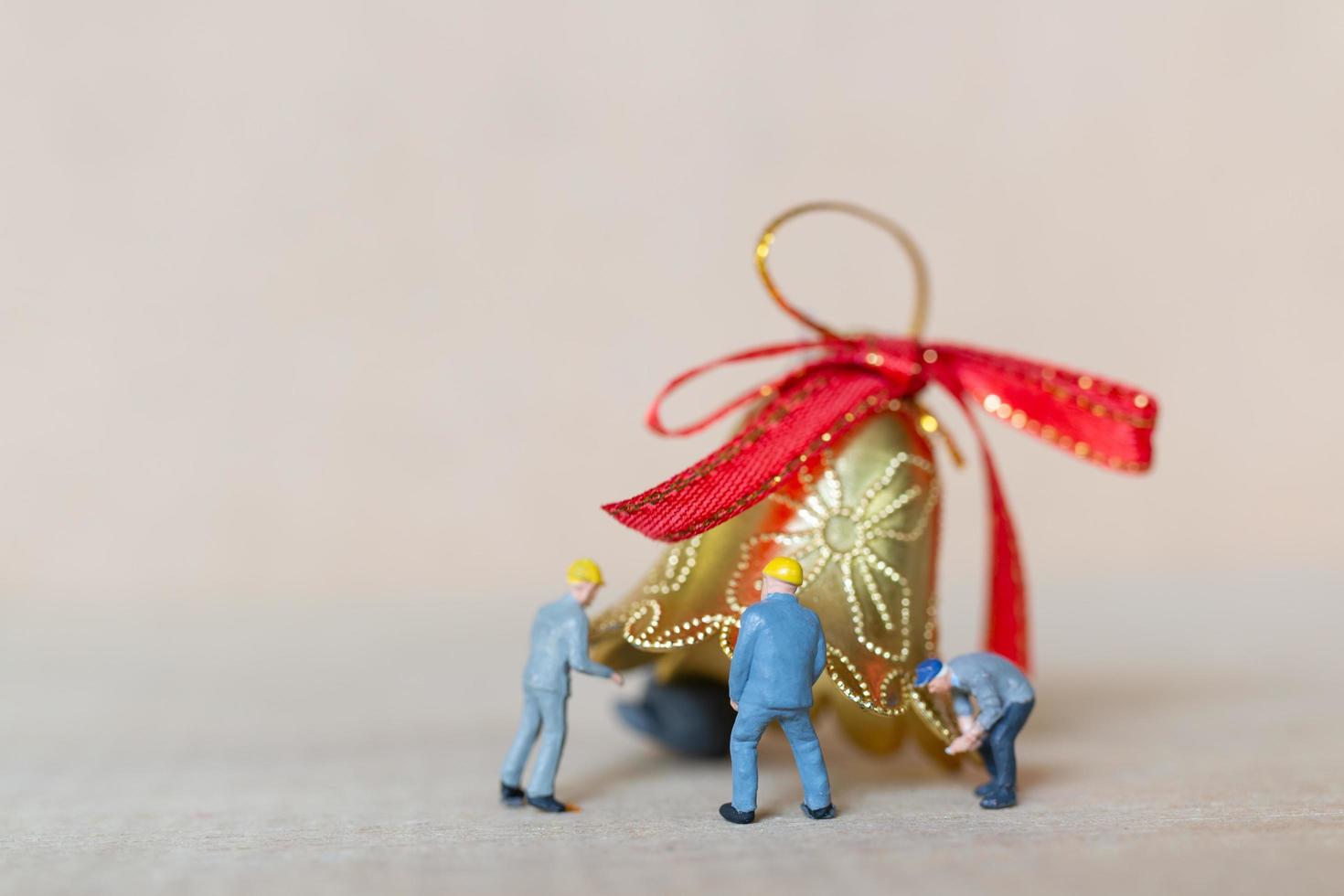 Miniature workers teaming up to work on a Christmas decoration, Christmas and Happy New Year concept photo