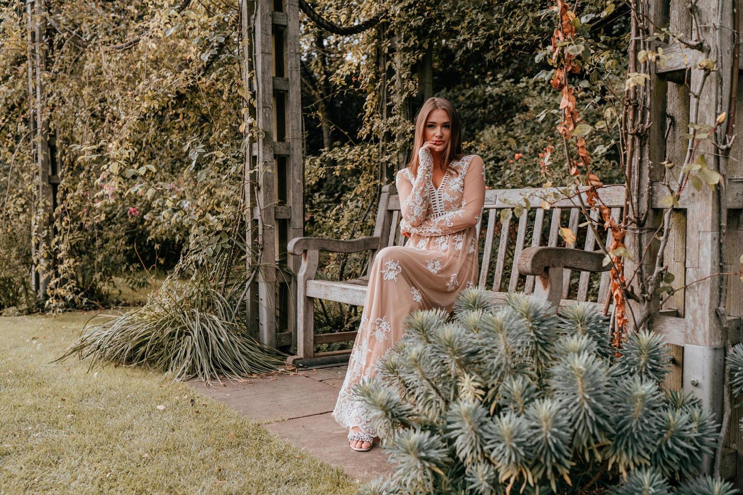 Woman sitting on a park bench in a dress photo