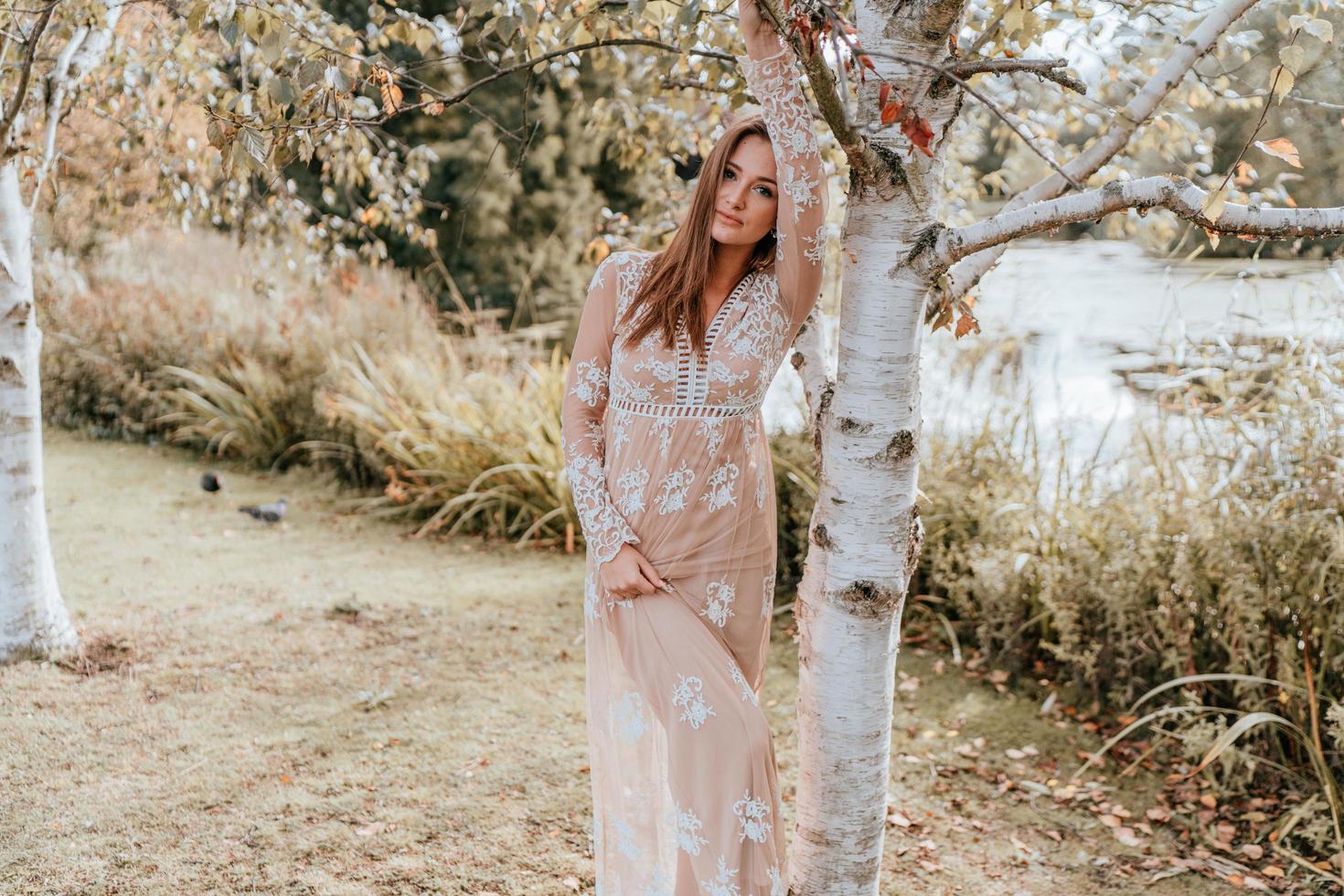 mujer posando contra un árbol en un parque foto