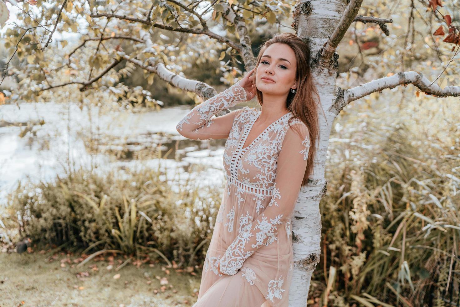 mujer vistiendo un vestido de encaje contra un árbol foto