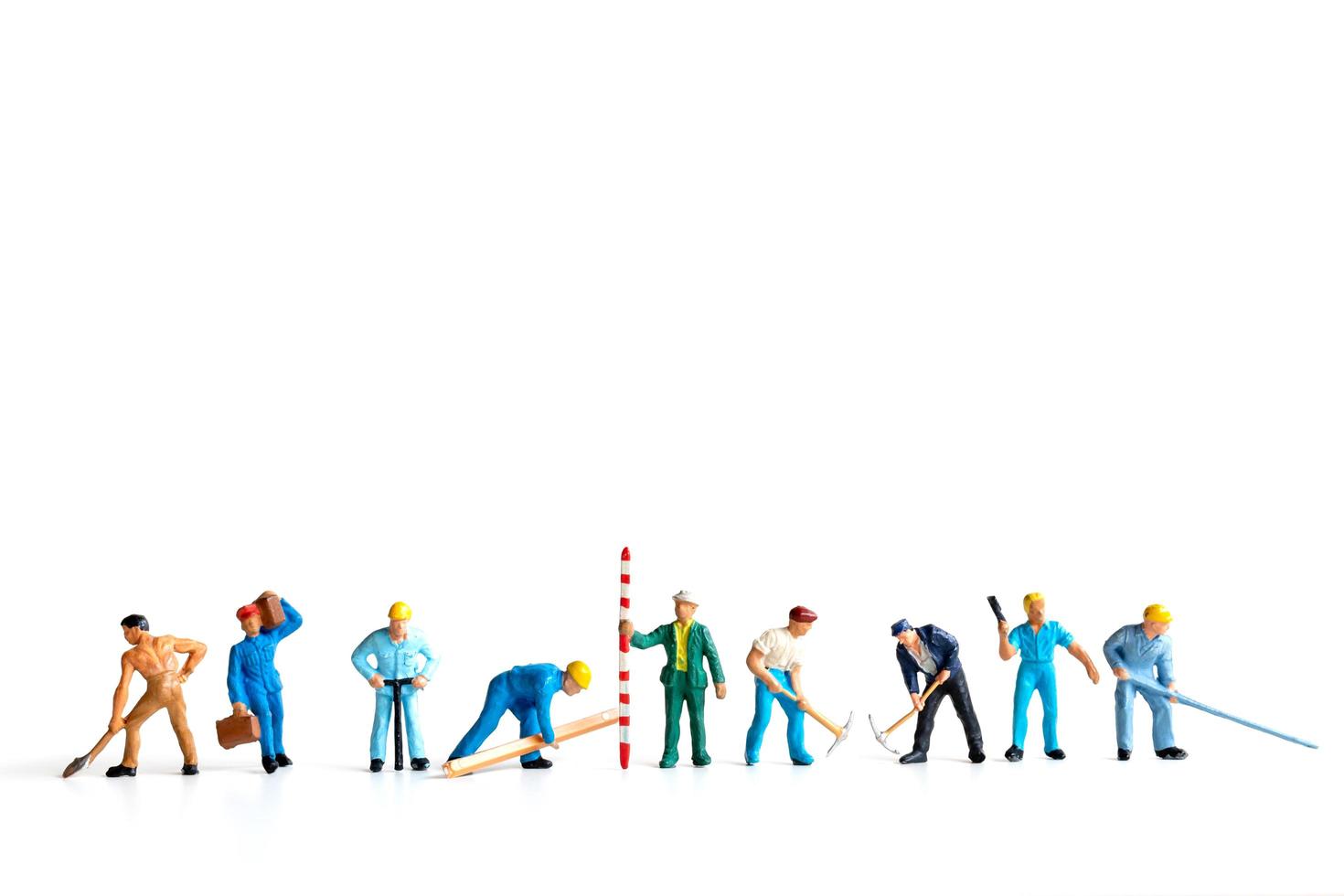 Miniature workers standing on a white background, labor concept photo