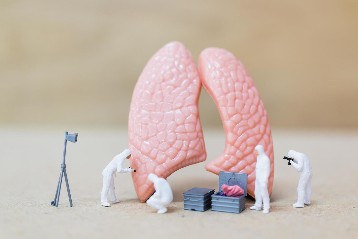 Científicos en miniatura observando y discutiendo el concepto de infección por bacterias, virus y pulmones humanos foto