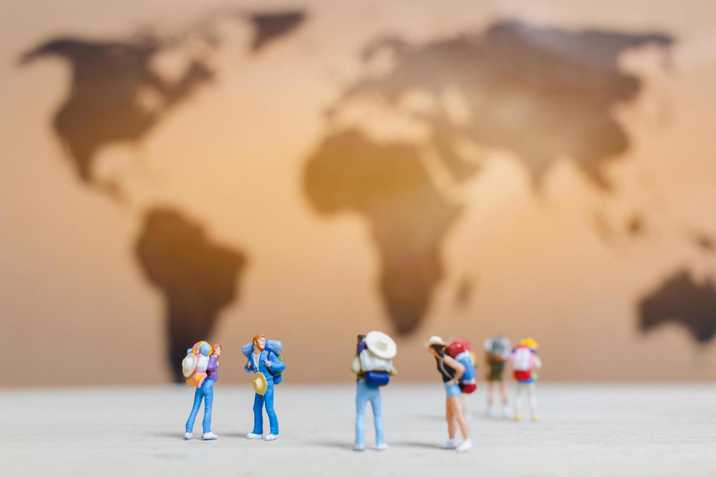 Miniature travelers walking on a world map, traveling and exploring the world concept photo