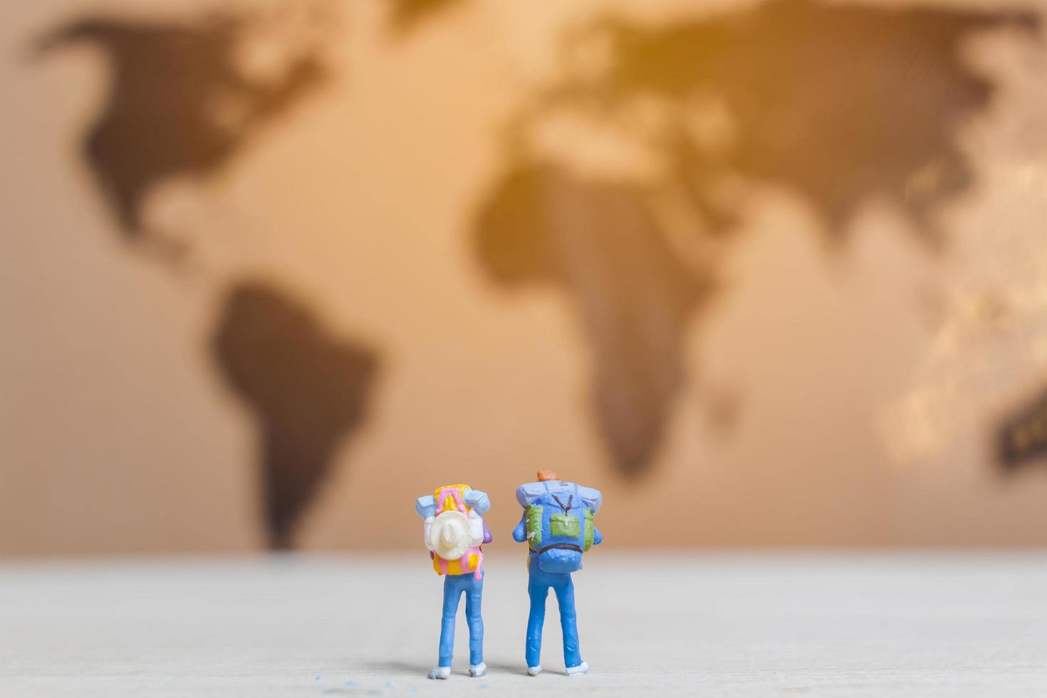 Miniature travelers walking on a world map, traveling and exploring the world concept photo