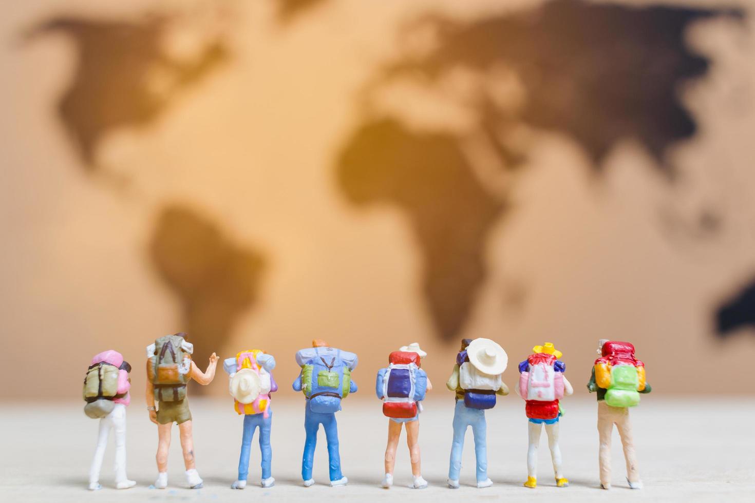 Miniature travelers walking on a world map, traveling and exploring the world concept photo