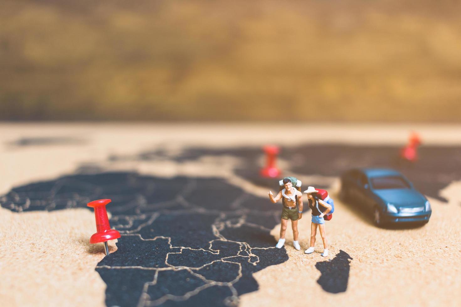 Miniature travelers walking on a world map, traveling and exploring the world concept photo