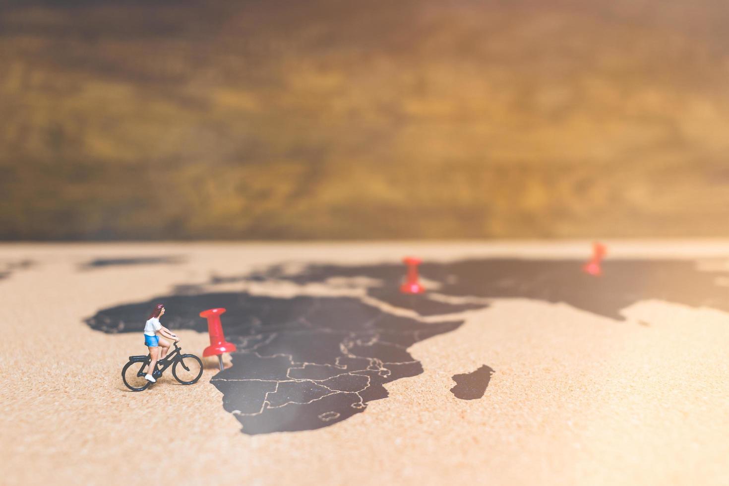 Miniature travelers riding bicycles on a world map, traveling and exploring the world concept photo