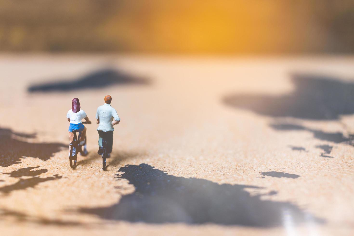 Miniature travelers riding bicycles on a world map, traveling and exploring the world concept photo