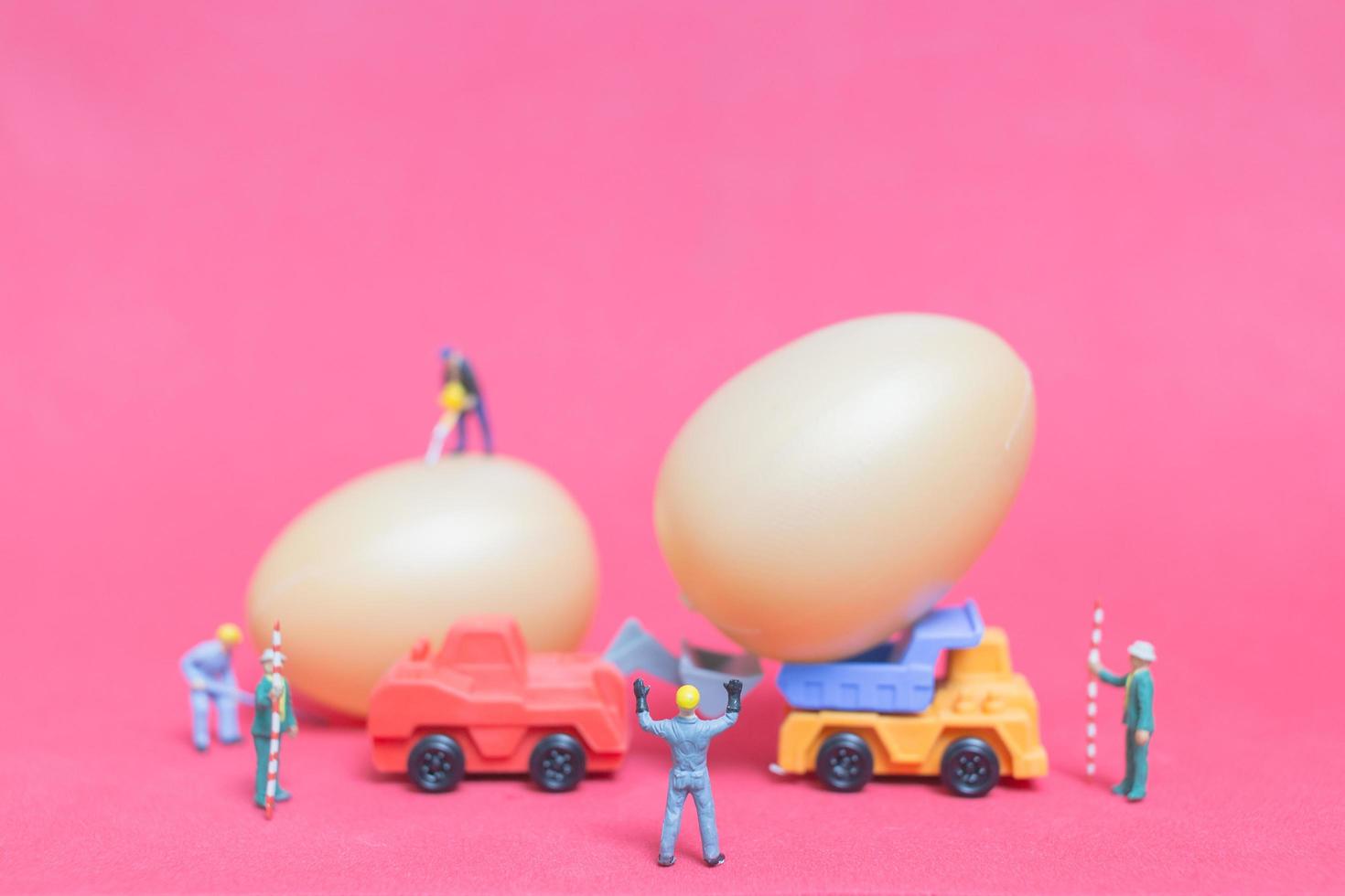 Miniature people working on Easter-eggs for Easter photo