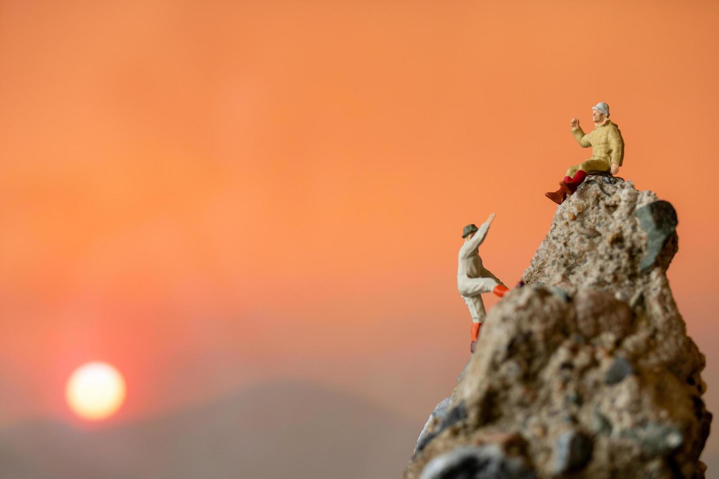 Excursionistas en miniatura subiendo a una roca, concepto deportivo y de ocio foto