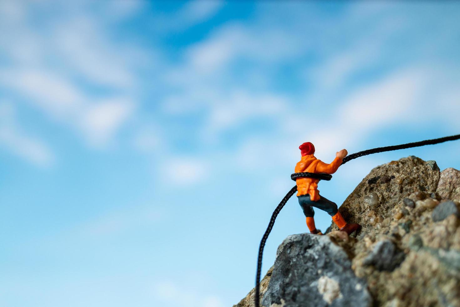 Miniature hikers climbing up on a rock, sports and leisure concept photo