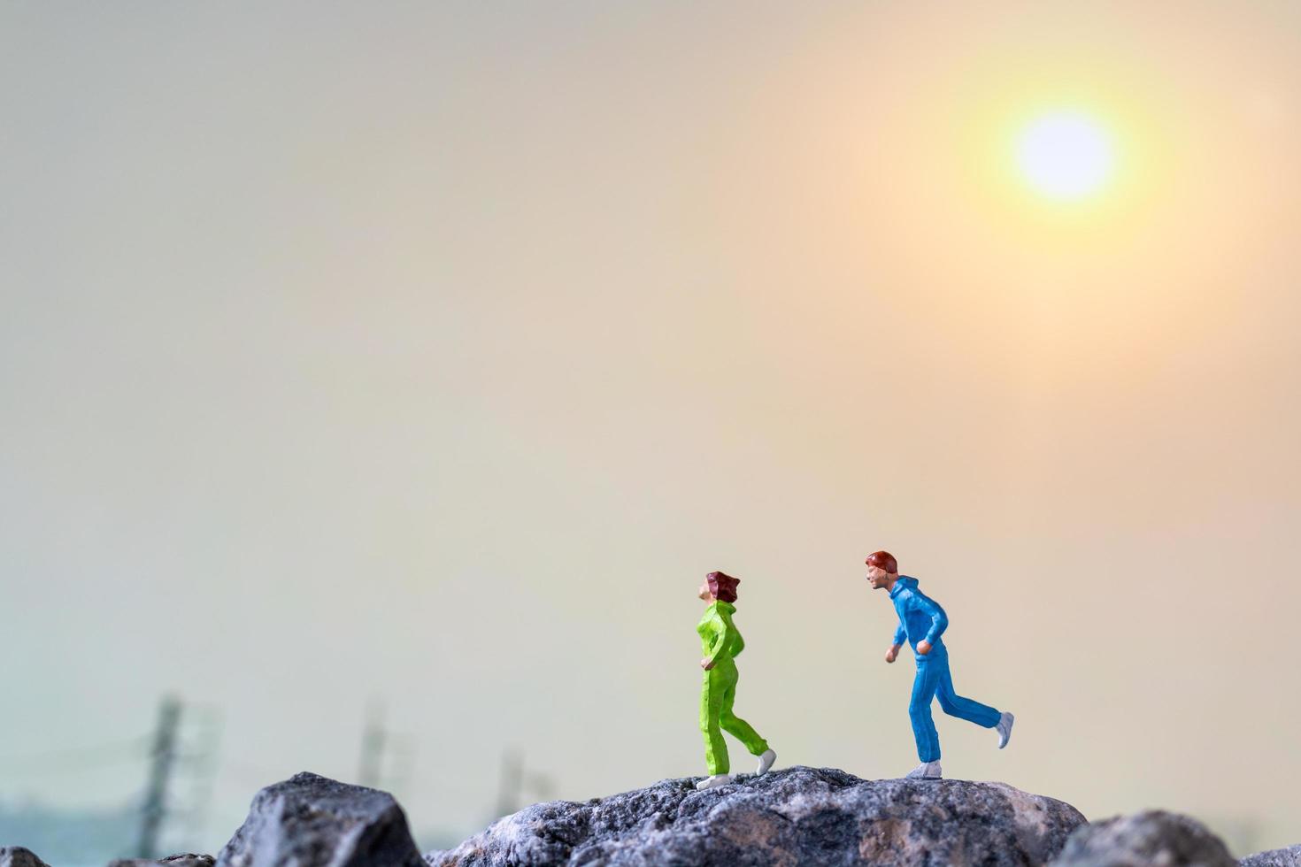 Miniature people running on a rock cliff with nature background, health and lifestyle concept photo