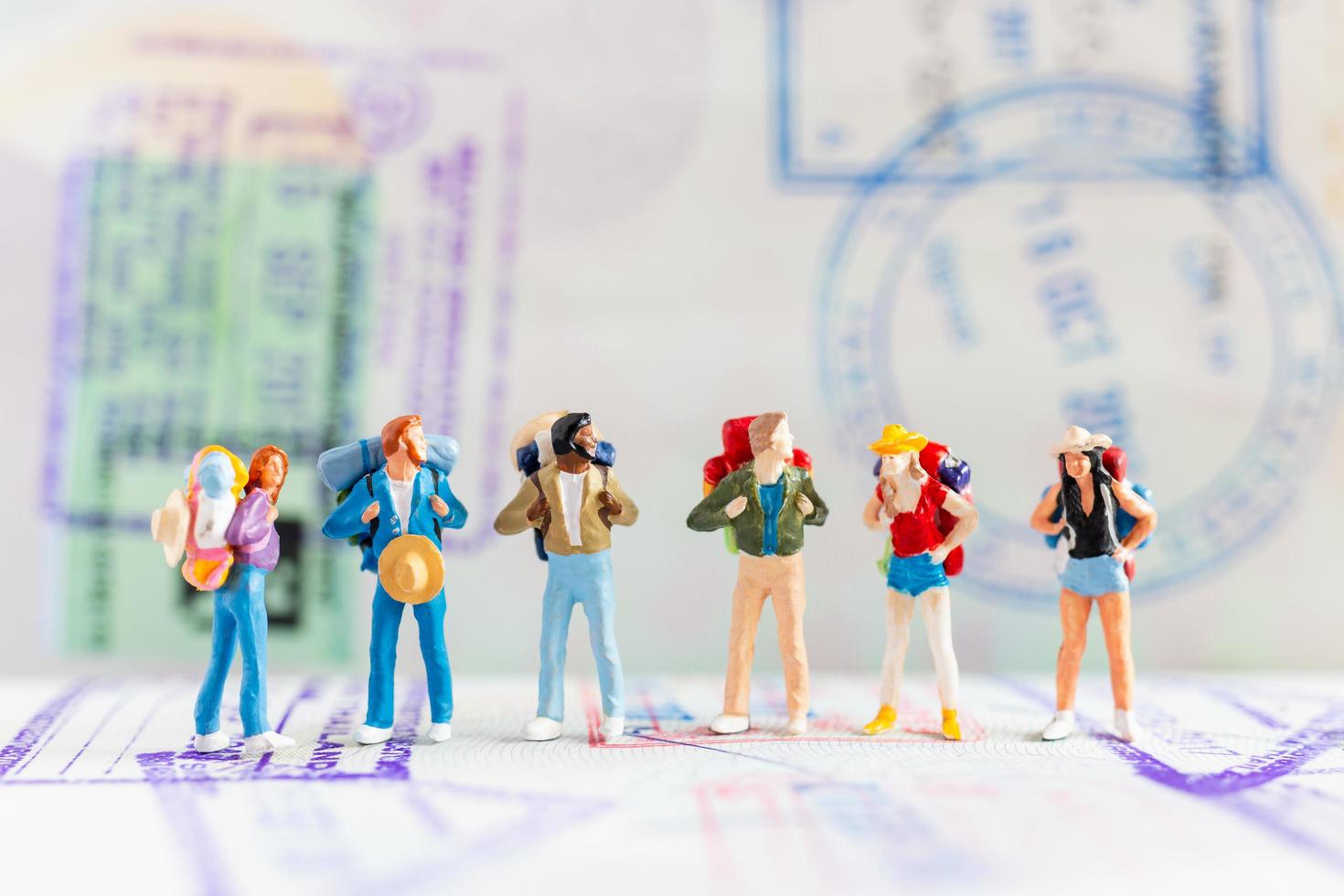 Miniature travelers with backpacks walking on a passport, travel and adventure concept photo