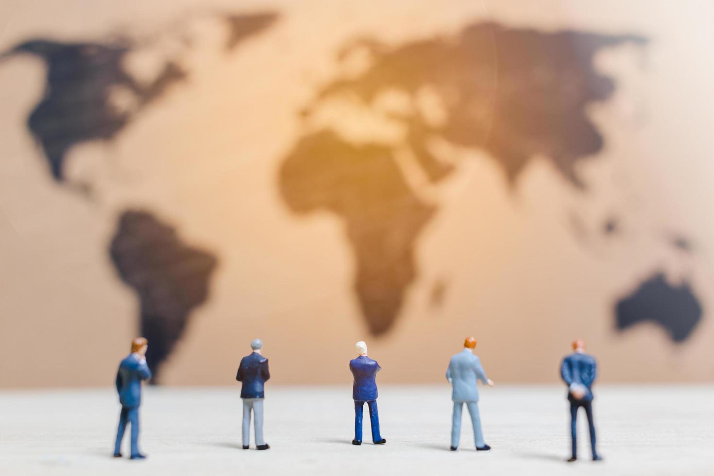 Miniature businessmen standing by a world map background, growing a business concept photo