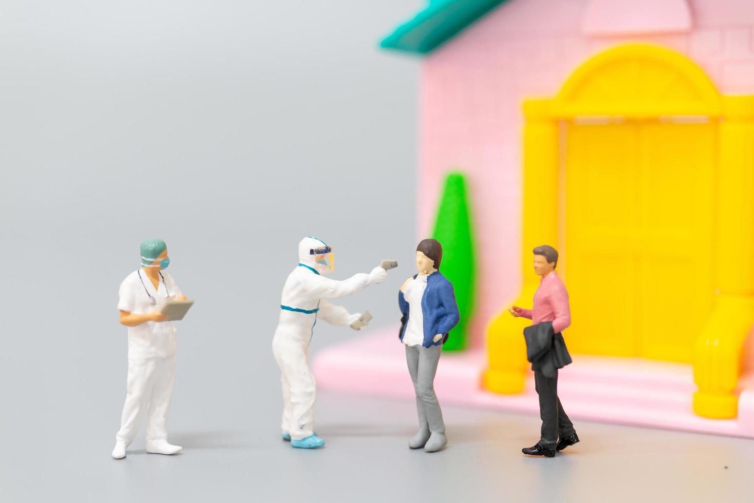 Miniature people with PPE visiting patients for a check for coronavirus at home, health care concept photo