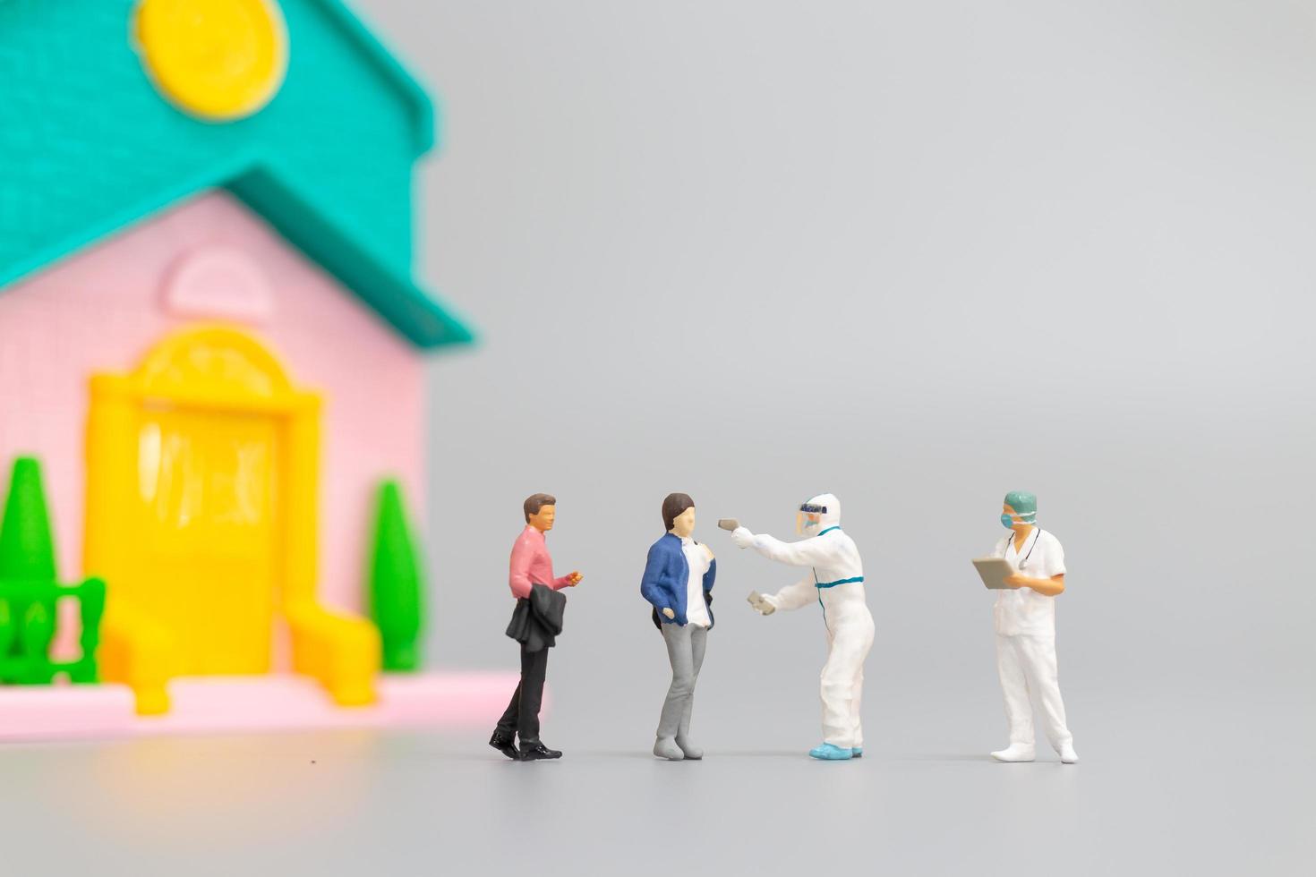 Miniature people with PPE visiting patients for a check for coronavirus at home, health care concept photo