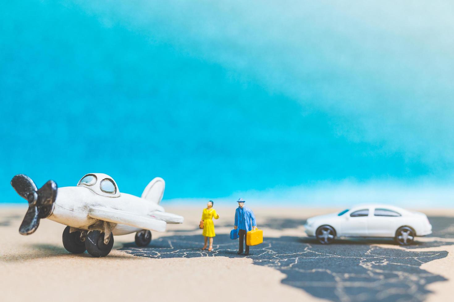 Miniature travelers with an airplane on a world map, travel and business concept photo