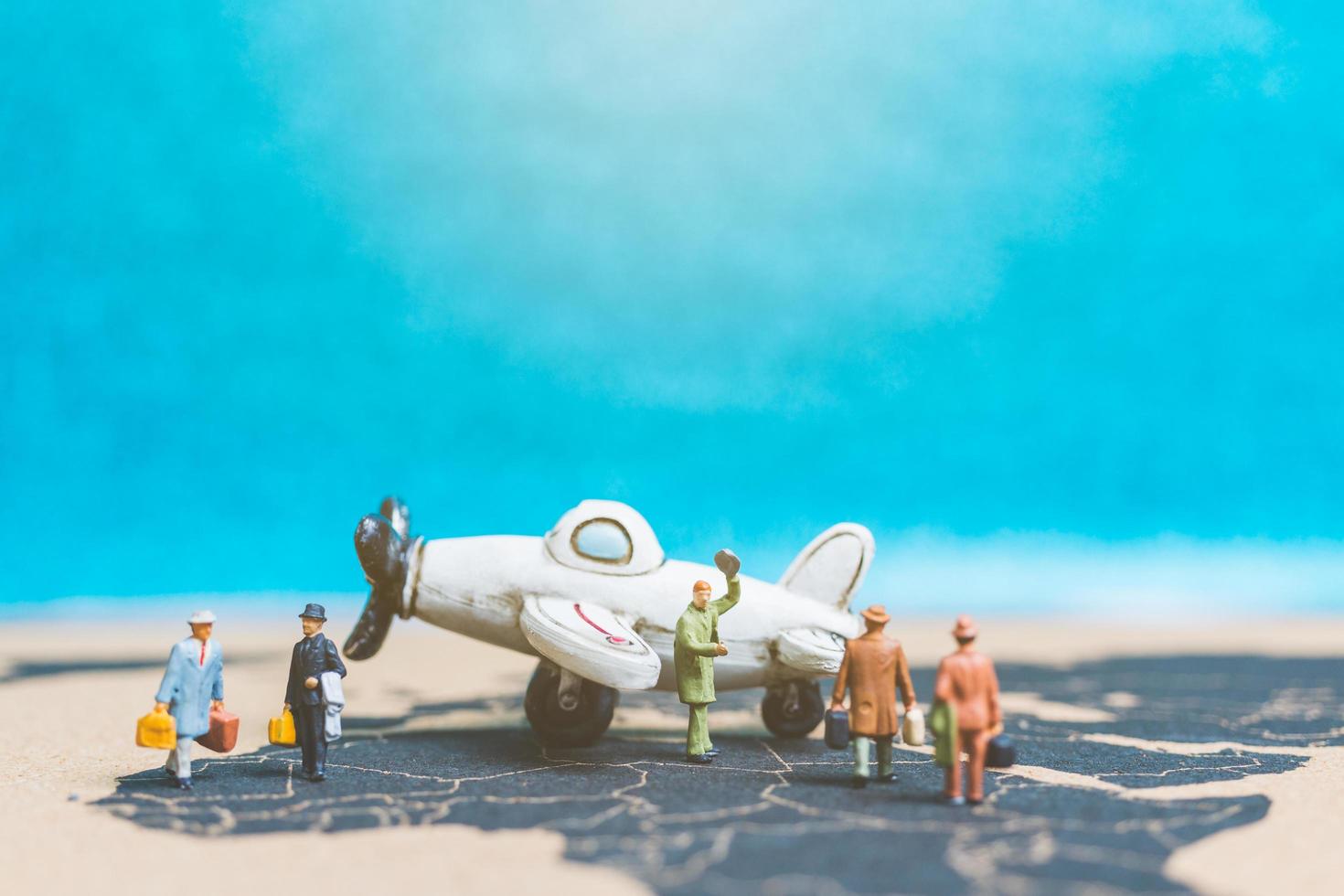 Miniature travelers with an airplane on a world map, travel and business concept photo