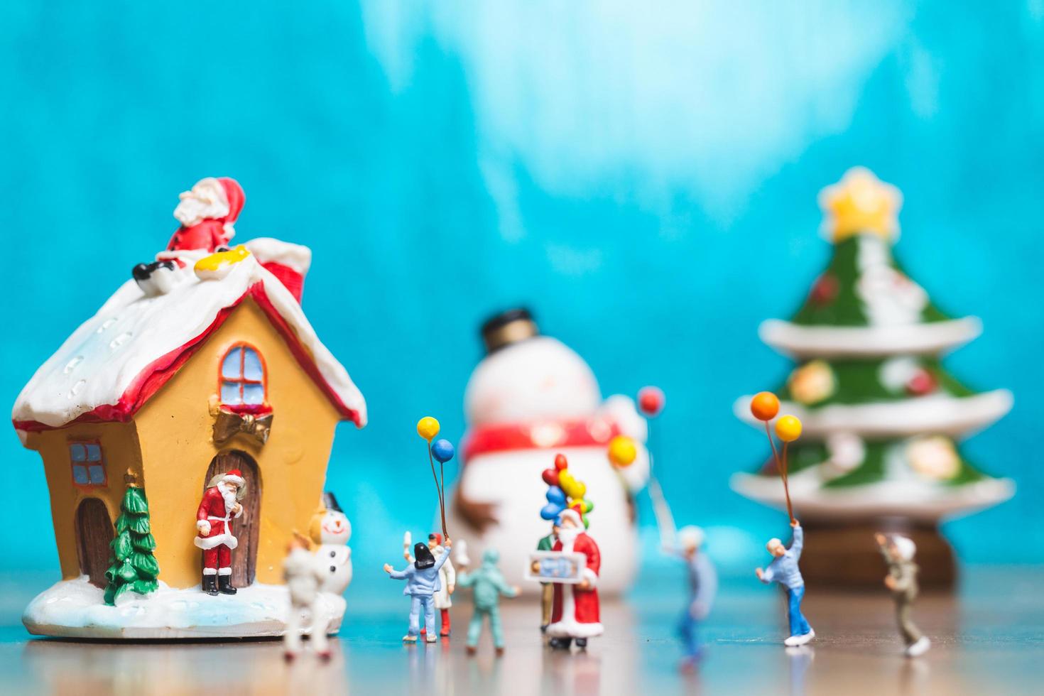 Familia en miniatura celebrando la Navidad sobre un fondo azul. foto